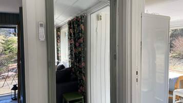 Ein Zimmer mit einem großen Spiegel, einer Tür und Blick auf eine Diele mit einer Couch und Vorhängen.