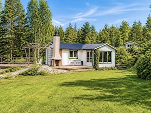 A cabin with a chimney, a deck, and a view of the surrounding forest. - 4 Star Holiday Home in Musko (Muskö)