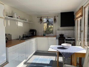 A compact kitchen with white cabinetry, a wooden countertop, a stove, and a window with a view of the outdoors. - 4 Star Holiday Home in Musko (Muskö)