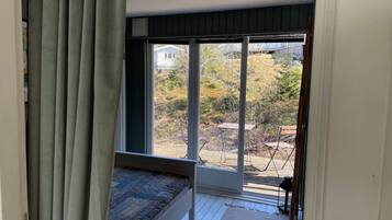 A room with a bed, a large sliding glass door leading to an outdoor area with a table and chairs.