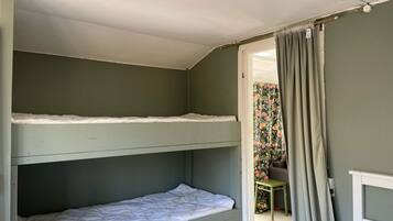 Quarto com beliche e porta de acesso a um banheiro.