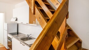A kitchen with white cabinets, a stainless steel sink, and a wooden staircase. - Apartment '1' Borgo San Giorgio (Grosseto)