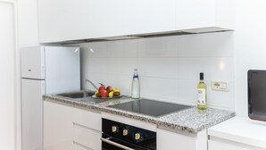 Ett modernt kök med vita skåp, en bänkskiva i granit, en inbyggd ugn och en diskho i rostfritt stål.