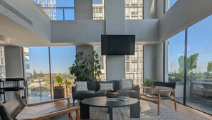 Uma sala de estar moderna com um sofá, poltronas, uma mesa de centro e uma televisão.