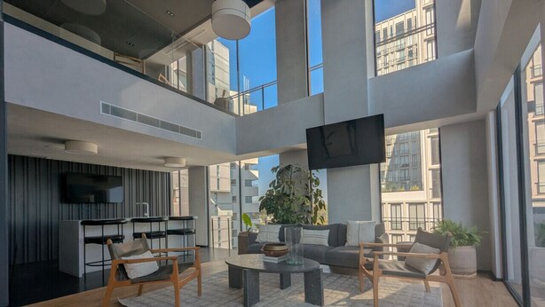 Interior moderno com área de refeições, cozinha e espaço de estar, com uma janela grande e planta.