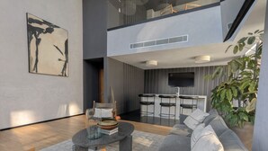 Uma sala de estar moderna com um sofá cinzento, uma mesa de centro e uma estante.