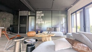Ein stilvolles Wohnzimmer mit großem Fenster, einem Holztisch und einer Couch mit Kissen.