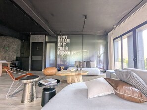 Ein stilvolles Wohnzimmer mit großem Fenster, einem Holztisch und einer Couch mit Kissen.