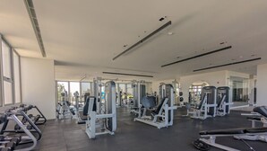 Une salle de sport moderne, dotée de divers appareils d’exercice, de grandes fenêtres et d’un aménagement propre et spacieux.