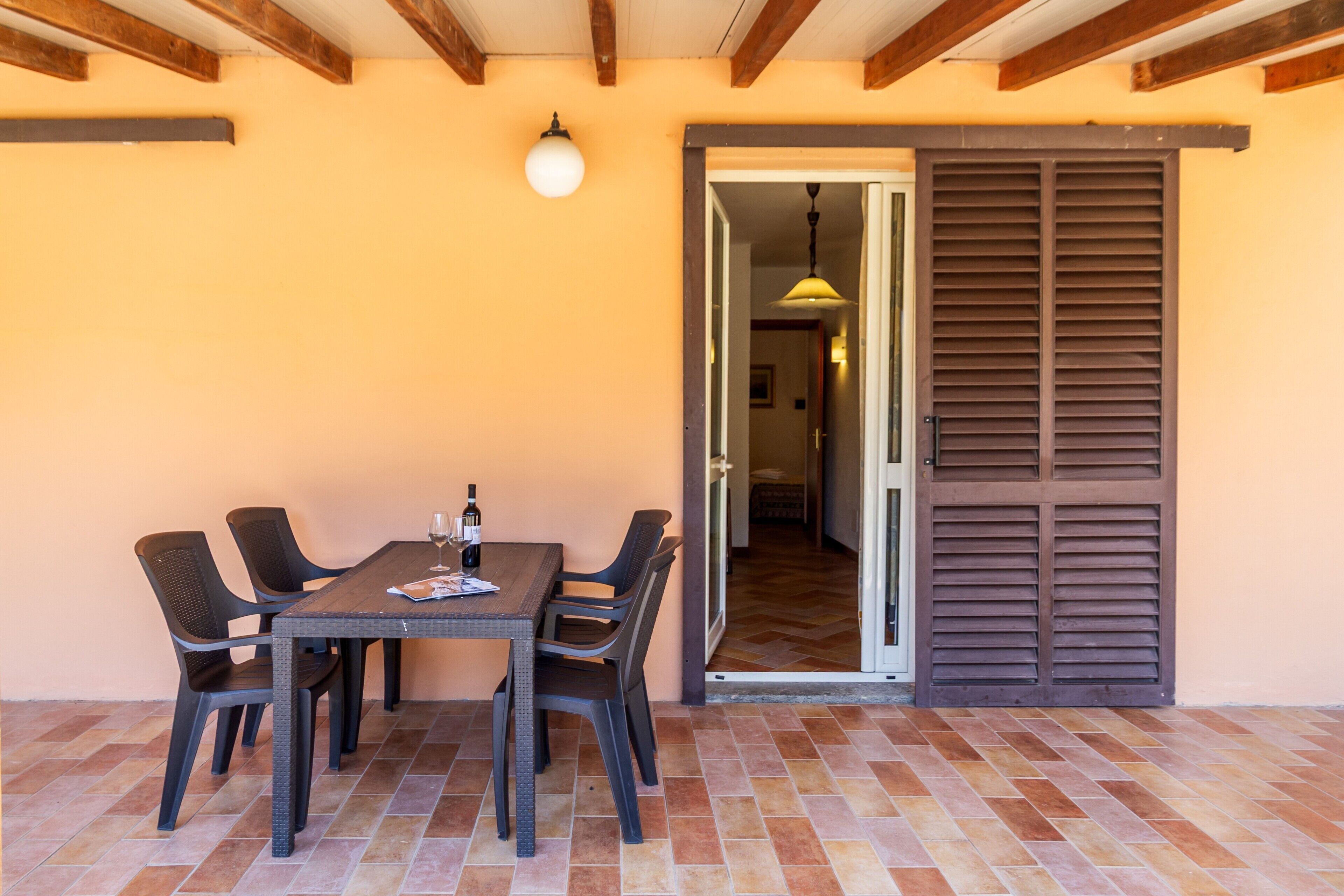 Un patio al aire libre con una mesa, sillas, una puerta y piso de baldosas.