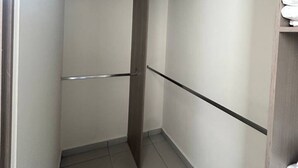 A narrow walk-in closet with a wooden door, a metal handle, and a shelf with folded towels. - Nuevo Depa Santa Ana 360 - 40 (Torre 11) (Zapopan)