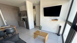 A modern living room with a sofa, a coffee table, a TV mounted on the wall, and a view of the kitchen and dining area. - Nuevo Depa Santa Ana 360 - 40 (Torre 11) (Zapopan)