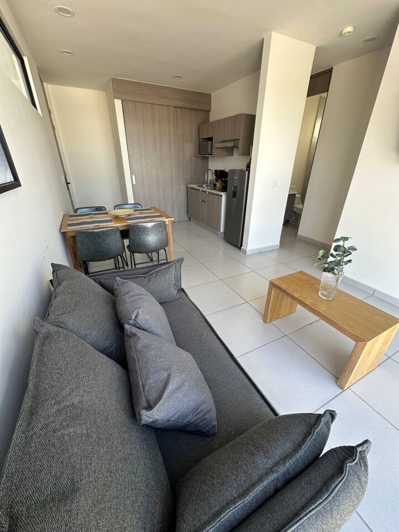 En moderne stue med sofa, sofabord og et spiseområde med stole og bord.