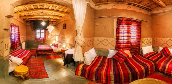 A traditional room with four beds, a small table, and a hanging lantern. - Riad des Vieilles Charrues (Ait Sedrate Jbel El Soufla)