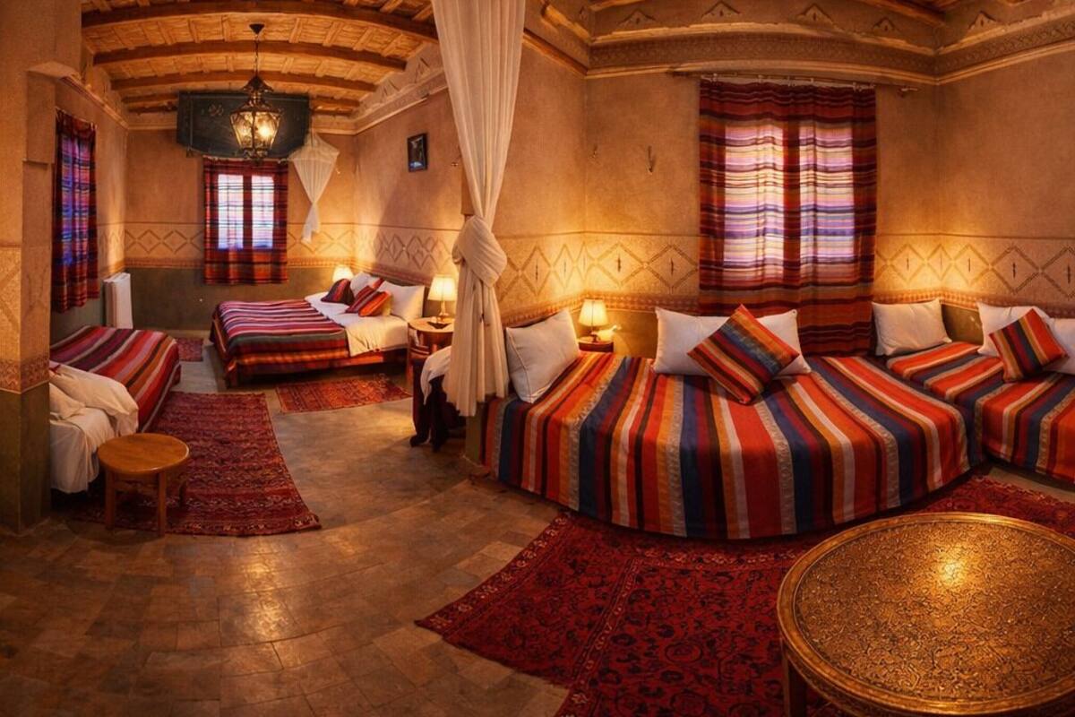 Una habitación con techo curvo, una cama con ropa de cama a rayas, una mesa redonda y una alfombra estampada.