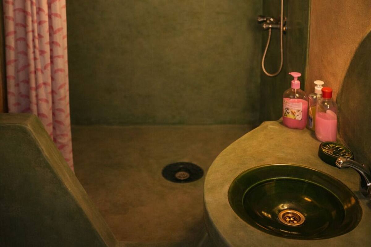 Un baño pequeño con ducha, lavamanos y un perchero para toallas.