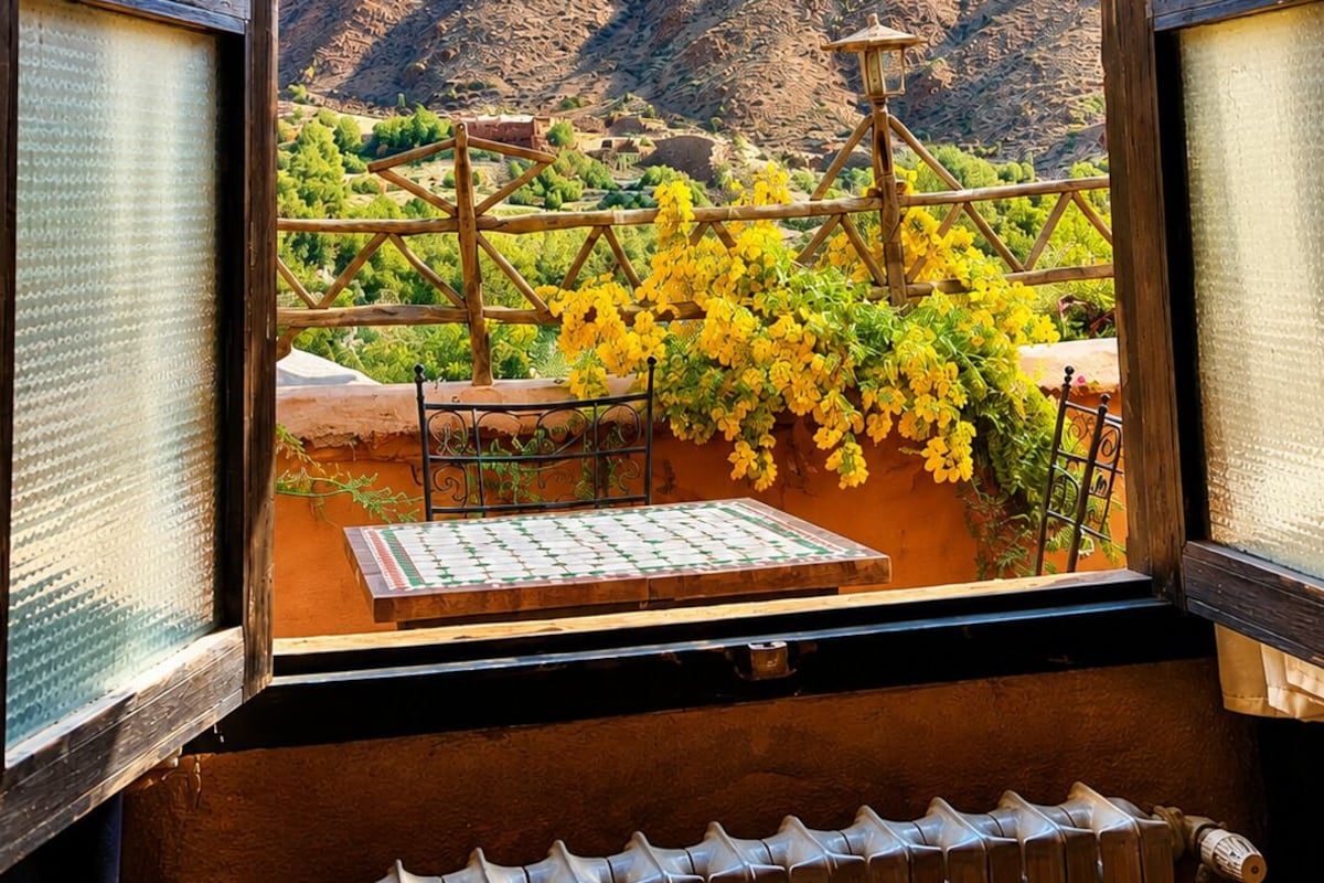 Habitación con vistas a montañas a través de una ventana con marcos de madera y vidrio esmerilado.