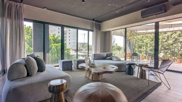 Een moderne woonkamer met een bank, een salontafel en een rond poef.