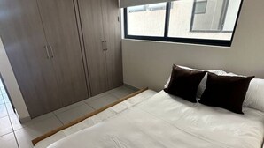Une chambre à coucher avec un lit, une armoire et une fenêtre.