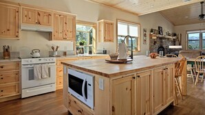 Une cuisine spacieuse avec des meubles en bois, un grand îlot central et une cheminée en pierre.
