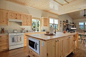 Eine geräumige Küche mit Holzausbau, einer großen Kochinsel und einem steinernen Kamin.