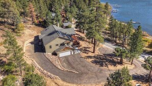 Une maison avec un garage, entourée d’arbres et bordée d’un lac.