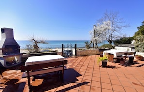 A patio with a grill, seating, and a view of the sea. - Cozy Beachside Retreat (Umag)