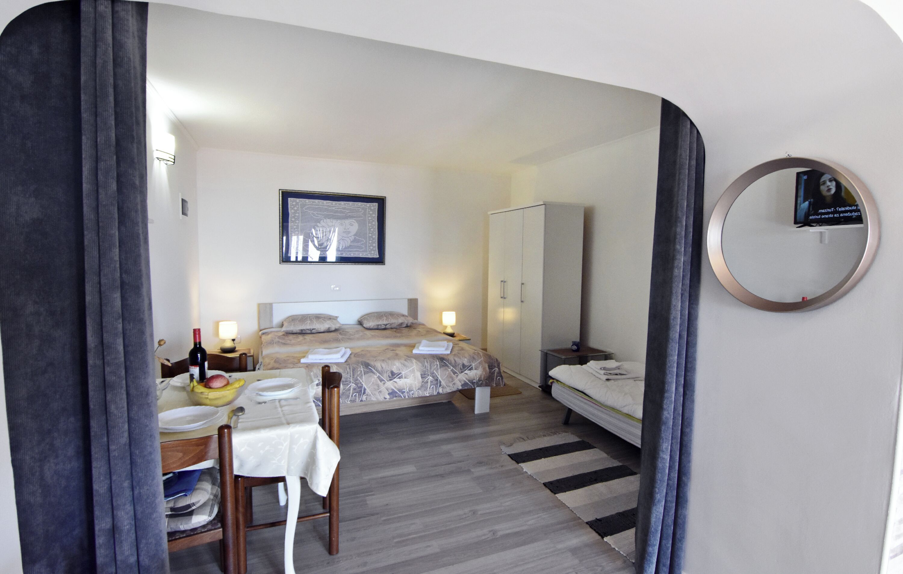 Una habitación de hotel con cama, mesita de noche, lámpara, armario y espejo.