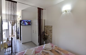A hotel room with a bed, a TV, a bathroom, and a view of the outside. - Compact Studio Stay With sea Views and BBQ (Umag)