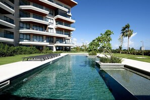A modern hotel with a swimming pool, balconies, and lush greenery. - Vermare Cap Cana | Golf, Pool and Luxury (punta cana)