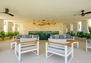 A spacious living area with modern furniture, ceiling fans, and a stone wall. - Vermare Cap Cana | Golf, Pool and Luxury (punta cana)