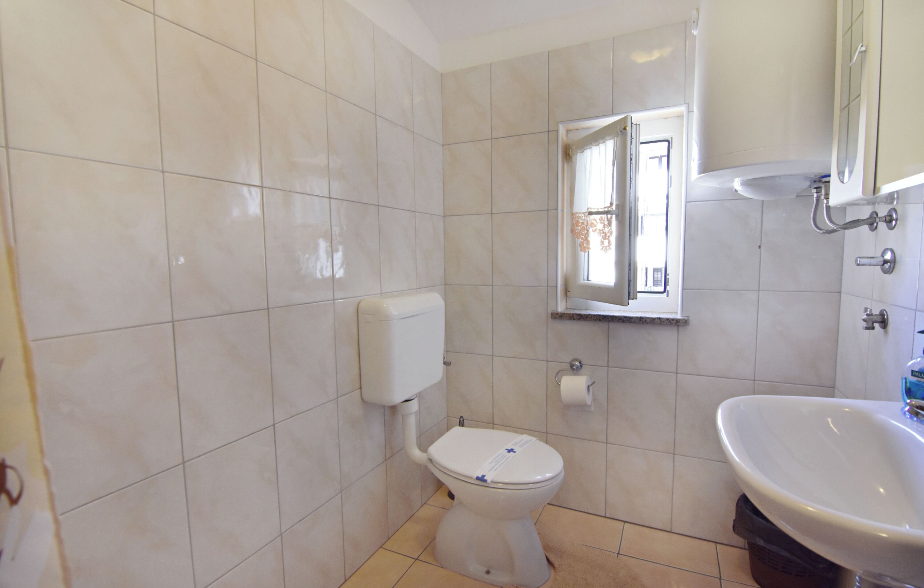 A bathroom with a toilet, a sink, and a mirror.