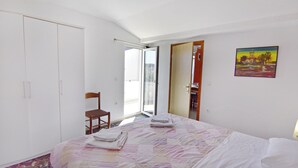 A bedroom with a bed, a chair, a wardrobe, and a painting on the wall. - Practical Stay With Ocean View (Umag)