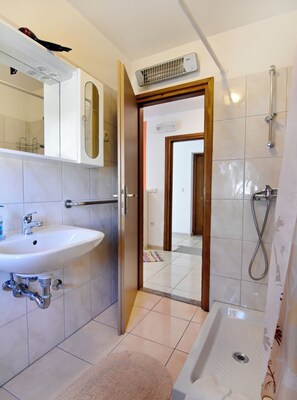 A bathroom with a sink, mirror, shower, and a door leading to another room. - Practical Stay With Ocean View (Umag)