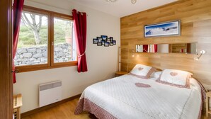 Una camera da letto con un letto grande, un muro in pietra, un soffitto in legno e un quadro raffigurante una montagna.