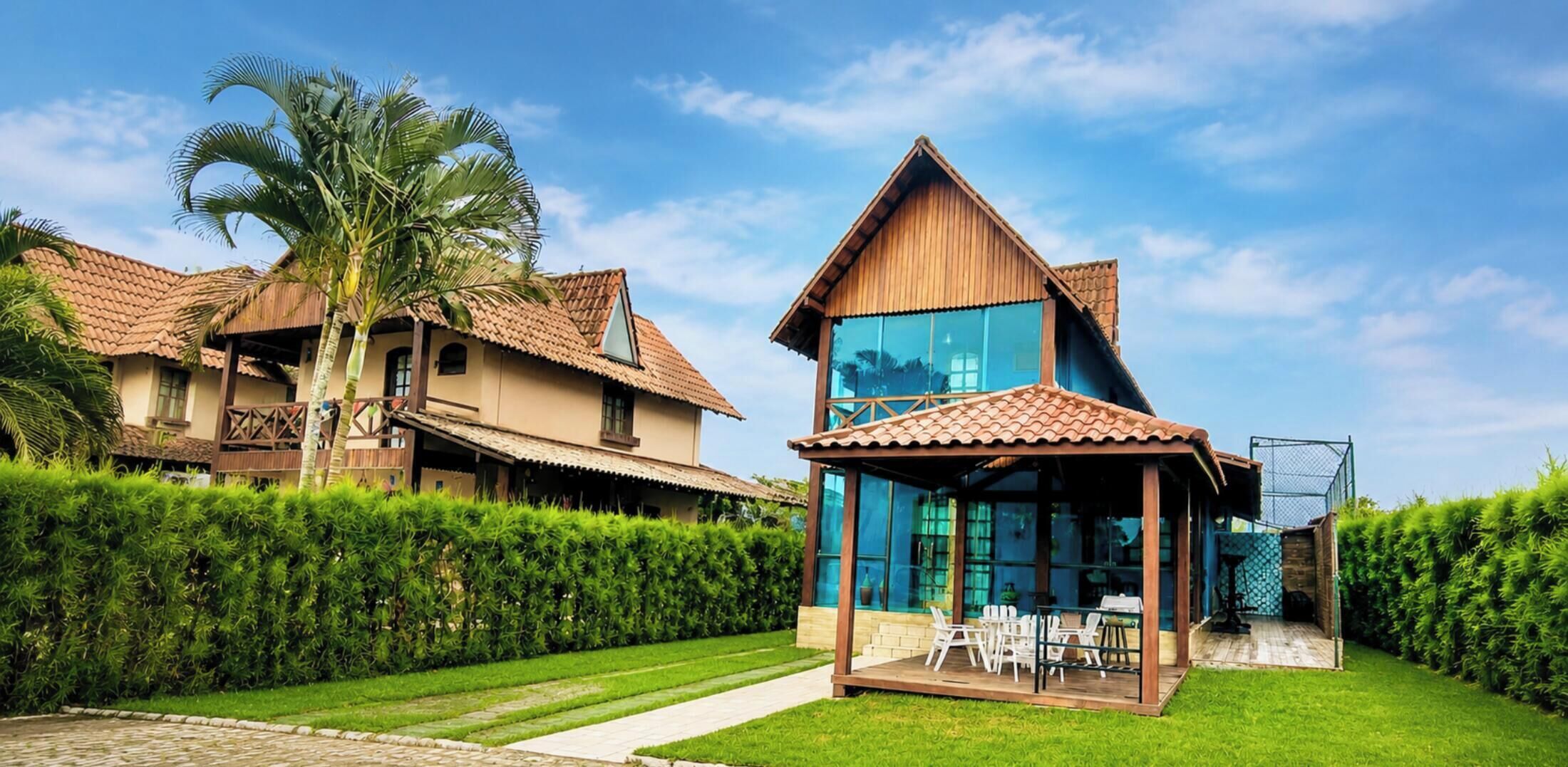 A two-story house with a tiled roof, a glass conservatory, and a well-maintained lawn.