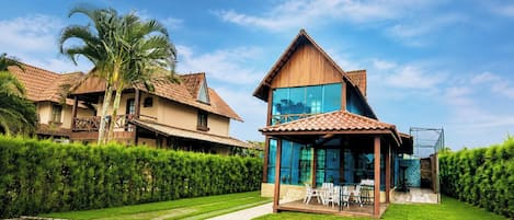 A two-story house with a tiled roof, a glass conservatory, and a well-maintained lawn.