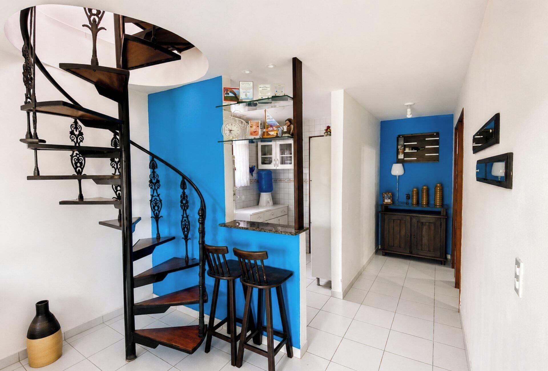 Una cocina moderna con una pared azul de acento, un refrigerador integrado y una zona de bar con taburetes.