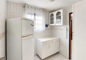 Una cocina con refrigerador, lavamanos y armarios.