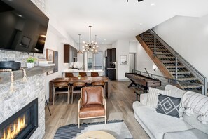 Ein modernes Wohnzimmer mit Kamin, Essbereich und Treppe.