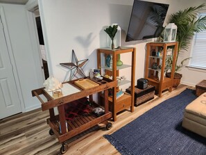 Ein Wohnzimmer mit einem Holfwagen, einem Fernseher und einer Topfpflanze.