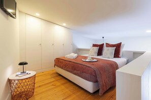 Ein Schlafzimmer mit Bett, Nachttisch, Kleiderschrank und an der Wand montiertem Fernseher.
