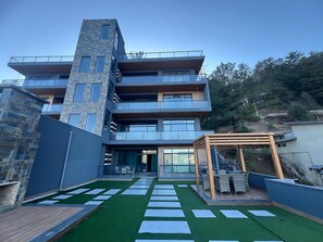 A multi-story building with balconies, a rooftop terrace with artificial grass, and a wooden pergola. - Ultra Luxury Boutique Apartment - Murree (Murree)