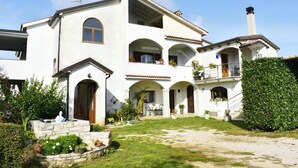 Une maison à deux étages avec un patio, un escalier en pierre et un jardin bien entretenu.