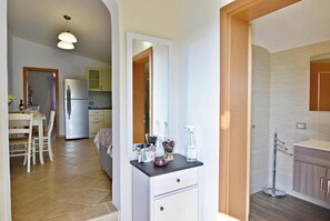 A modern kitchen with a refrigerator, a dining area with a table and chairs, and a bathroom with a sink and mirror. - Elegant Living for Your Vacation (Umag)