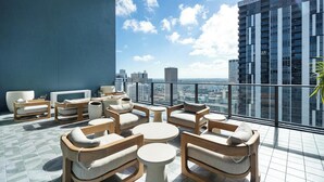 A rooftop lounge with outdoor seating, a city view, and a modern building in the background. - Bright apartment w/ pool & workspace (Miami)