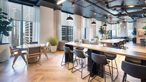 A modern office space with a large wooden table, multiple chairs, and large windows offering city views. - Bright apartment w/ pool & workspace (Miami)