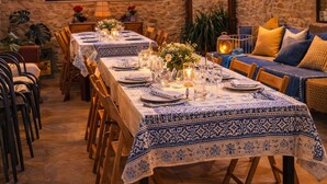 Un restaurant aux murs de pierre, aux tables recouvertes de nappes bleues et blanches, et décoré de guirlandes lumineuses.