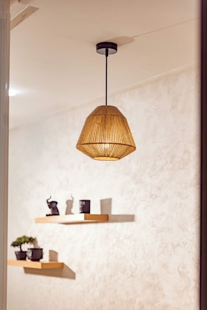Eine Pendelleuchte mit gewebtem Design, Holzregale mit Dekorationen und eine strukturierte Wand.