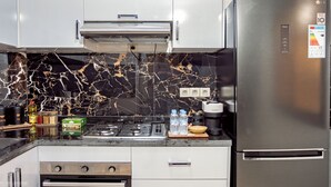 A modern kitchen with stainless steel appliances, a gas stove, and a built-in oven. - Comfortable apartment in the heart of Guéliz (Marrakech)